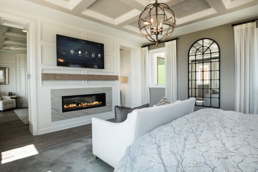 Bedroom with a lit fireplace and a TV displaying the Control4 platform.
